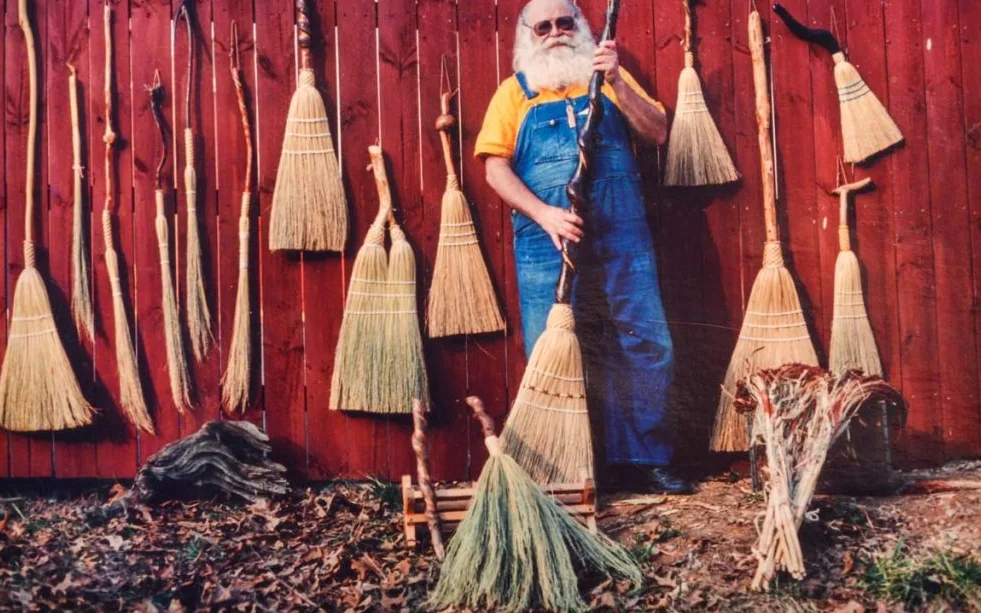 Marlow Gates among hanging brooms